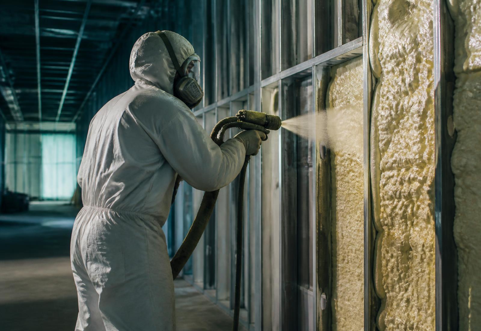 Insulation installer applying spray foam inside a commercial building under construction